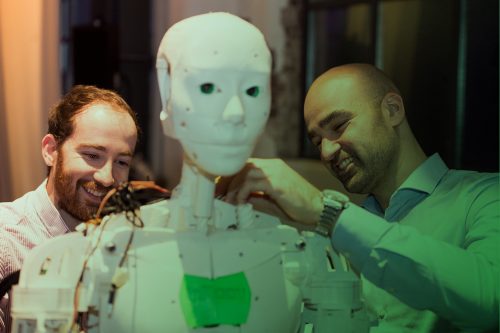 Zum Artikel Internet of Everything: Zwei Personen arbeiten an der Technik eines humanoiden Roboters