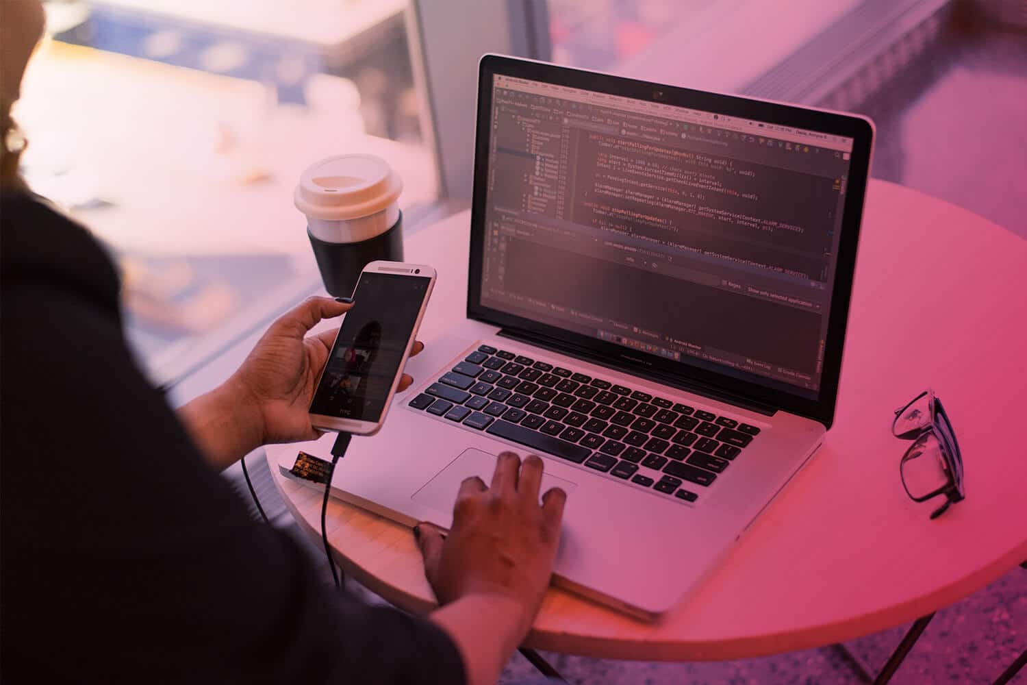 Zum Thema App Entwicklung: Laptop, Smartphone, App Entwickler am Schreibtisch