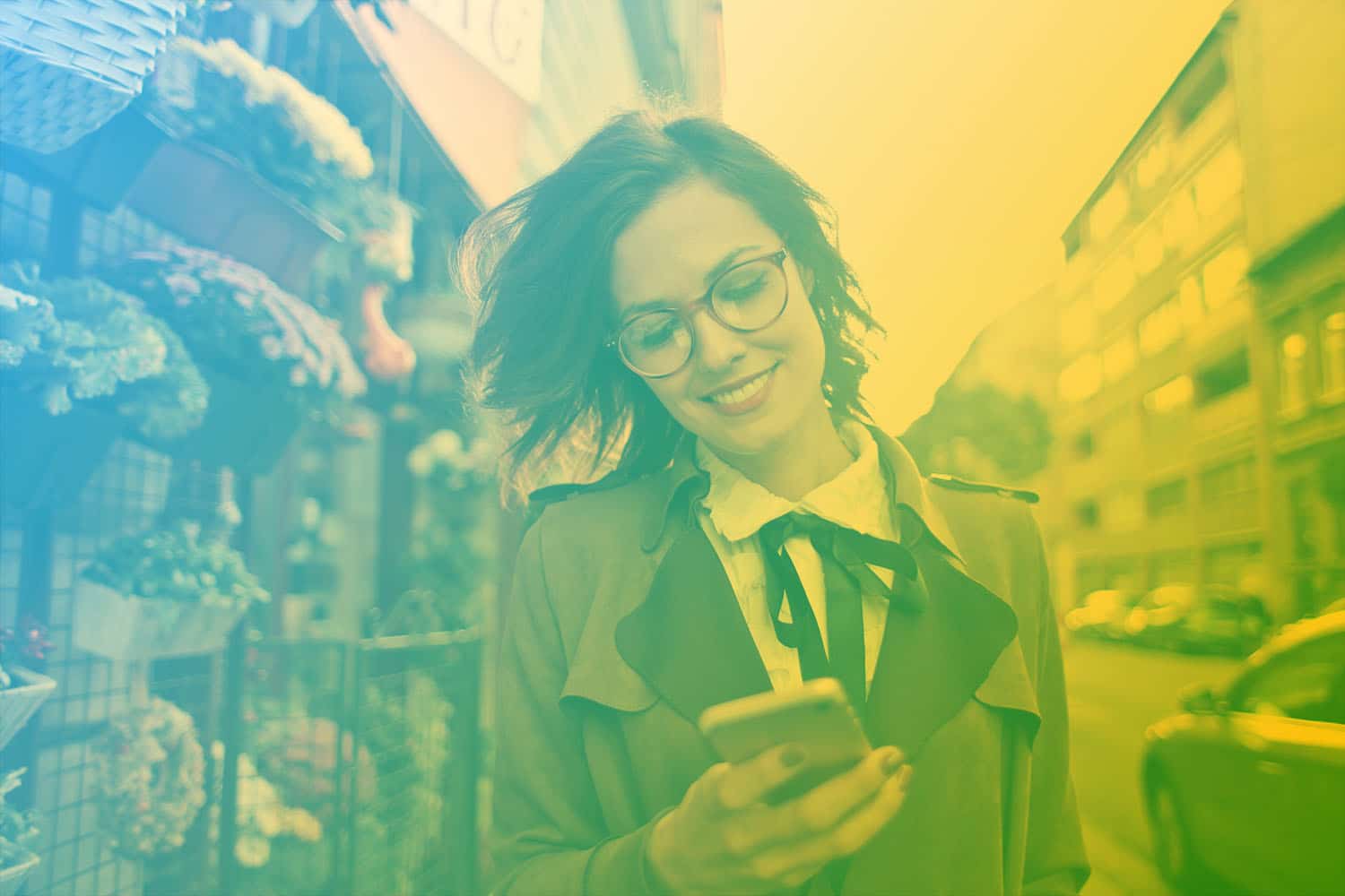 Zum Beitrag IoT im Handel - mit neuen Vertriebskanäle zum Handel 4.0: Frau mit Smartphone in der Hand vor Einkaufsladen an der Straße